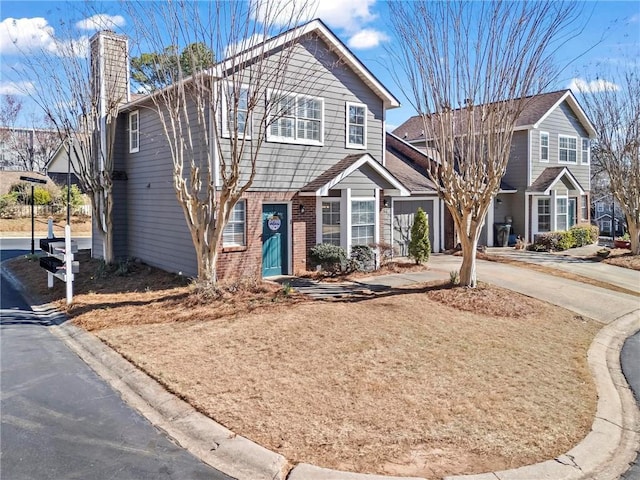 view of front of property featuring driveway, a chimney, and brick siding