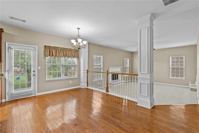 3039 Tuscan Ridge Dr, Snellville, GA 30039 - empty room with decorative columns, baseboards, hardwood / wood-style floors, and a chandelier