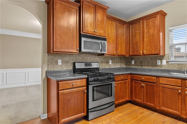 3039 Tuscan Ridge Dr, Snellville, GA 30039 - kitchen featuring stainless steel appliances, dark countertops, brown cabinets, and ornamental molding