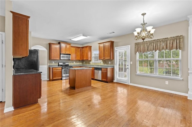 3039 Tuscan Ridge Dr, Snellville, GA 30039 - kitchen featuring appliances with stainless steel finishes, a chandelier, decorative backsplash, light wood-style flooring, and healthy amount of natural light
