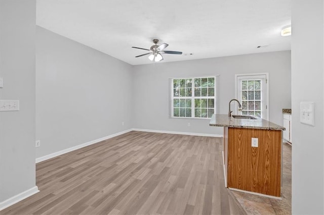 kitchen featuring light hardwood / wood-style floors, light stone counters, ceiling fan, and sink