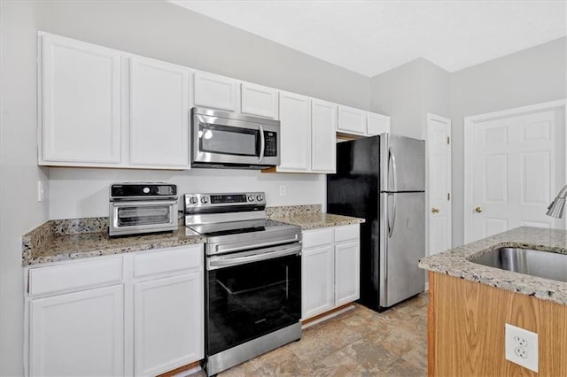 kitchen featuring light stone counters, white cabinetry, sink, and appliances with stainless steel finishes