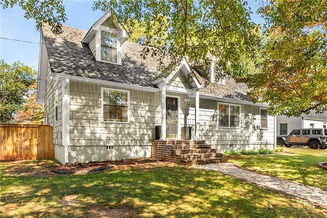 cape cod house with crawl space, a shingled roof, a front yard, and fence