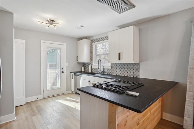 kitchen with sink, a breakfast bar area, appliances with stainless steel finishes, kitchen peninsula, and backsplash