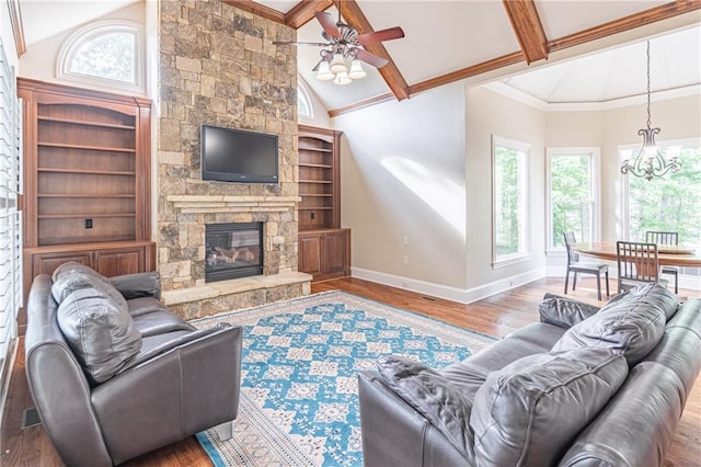 living area featuring a ceiling fan, baseboards, wood finished floors, beam ceiling, and a chandelier