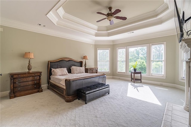 carpeted bedroom with crown molding, a tray ceiling, baseboards, and a ceiling fan