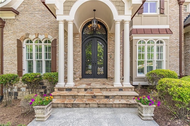 property entrance featuring french doors, brick siding, and covered porch