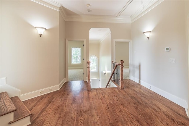 hall with an upstairs landing, wood finished floors, ornamental molding, and baseboards