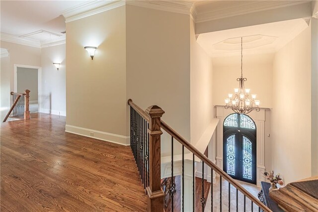 hall with an upstairs landing, a chandelier, french doors, wood finished floors, and ornamental molding