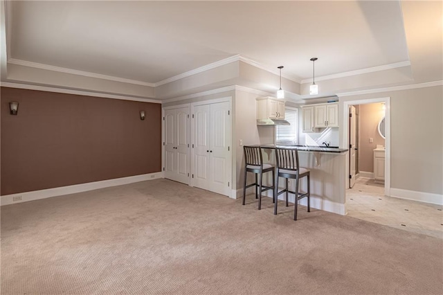 kitchen with a kitchen bar, light colored carpet, a peninsula, crown molding, and baseboards