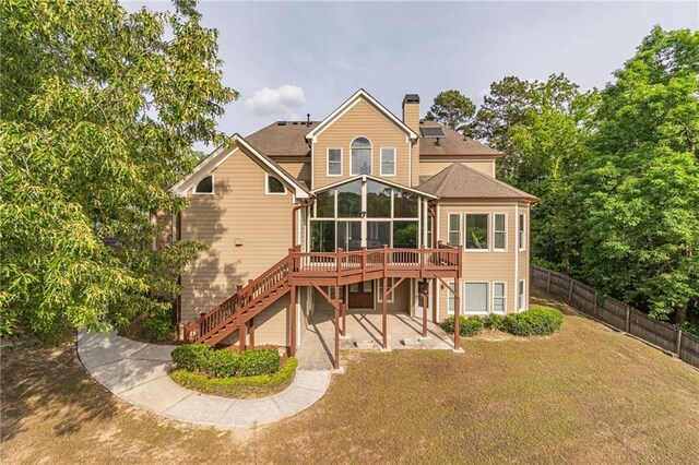 back of property featuring a sunroom, stairway, a chimney, a patio, and a wooden deck