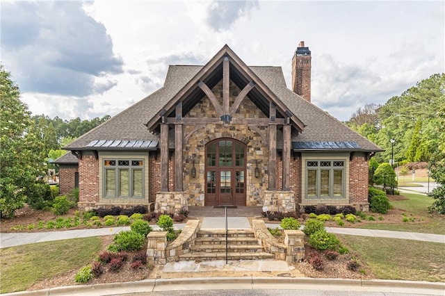 view of front of home with french doors, a chimney, stone siding, and a shingled roof
