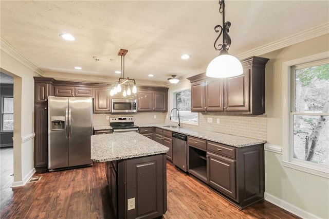 kitchen with a kitchen island, appliances with stainless steel finishes, decorative light fixtures, and dark hardwood / wood-style flooring