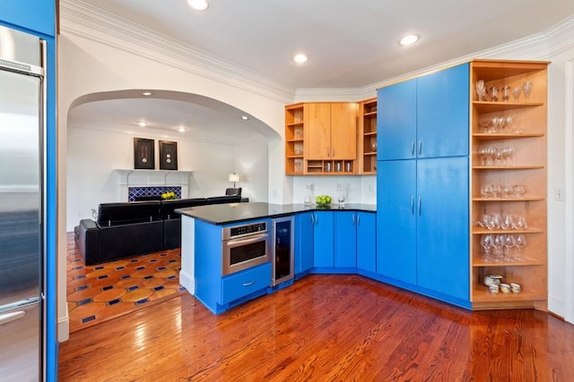 kitchen with blue cabinetry, appliances with stainless steel finishes, open shelves, dark countertops, and dark wood finished floors