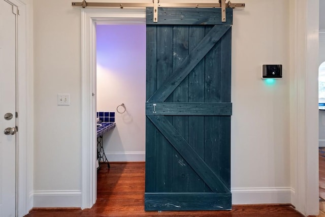 details featuring a barn door, baseboards, and wood finished floors