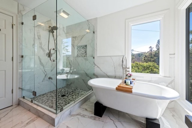 bathroom featuring marble finish floor, a marble finish shower, and a freestanding bath