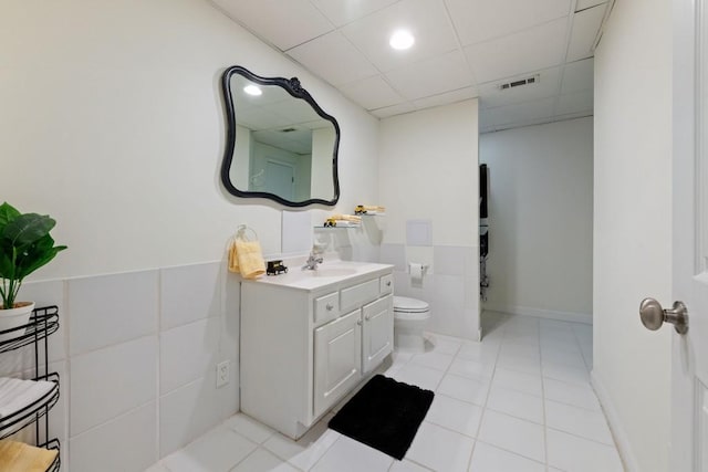 bathroom with visible vents, a drop ceiling, toilet, tile patterned flooring, and vanity