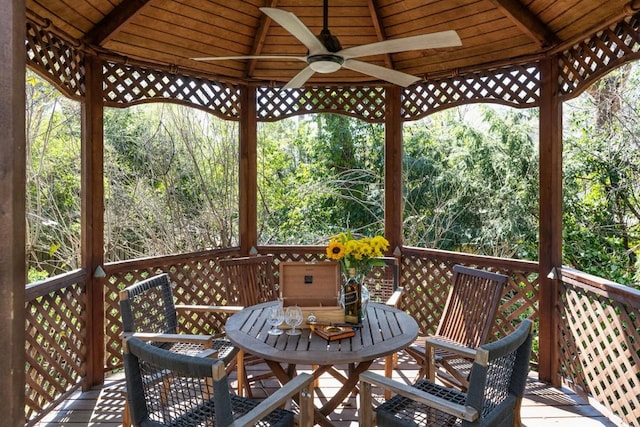 wooden deck with a ceiling fan, outdoor dining area, and a wooded view