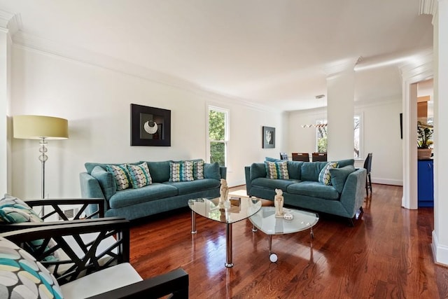 living room with dark wood-type flooring, crown molding, baseboards, and decorative columns