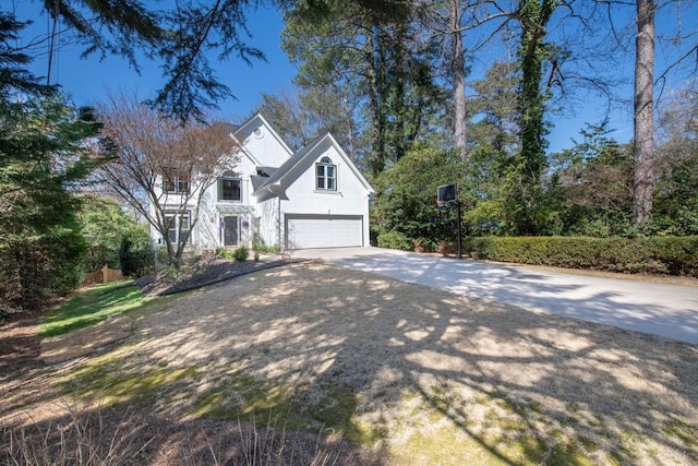 traditional-style house with a garage, concrete driveway, and stucco siding