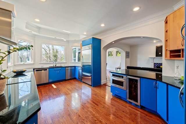 kitchen featuring stainless steel appliances, beverage cooler, a sink, and blue cabinetry