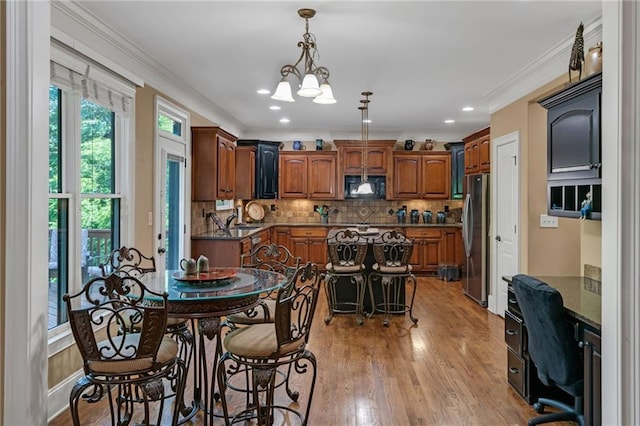 interior space with sink, a chandelier, ornamental molding, and light hardwood / wood-style floors