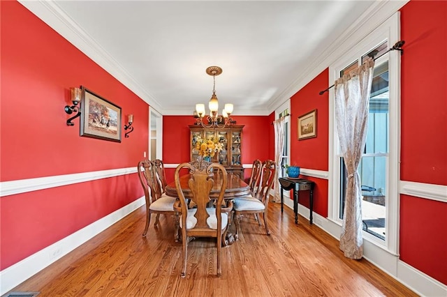 dining area with a wealth of natural light, light hardwood / wood-style flooring, crown molding, and a chandelier