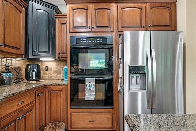 kitchen with black double oven, tasteful backsplash, stainless steel fridge with ice dispenser, and stone counters