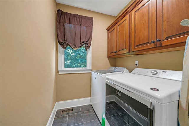 laundry area featuring cabinets, dark tile patterned floors, and washing machine and clothes dryer