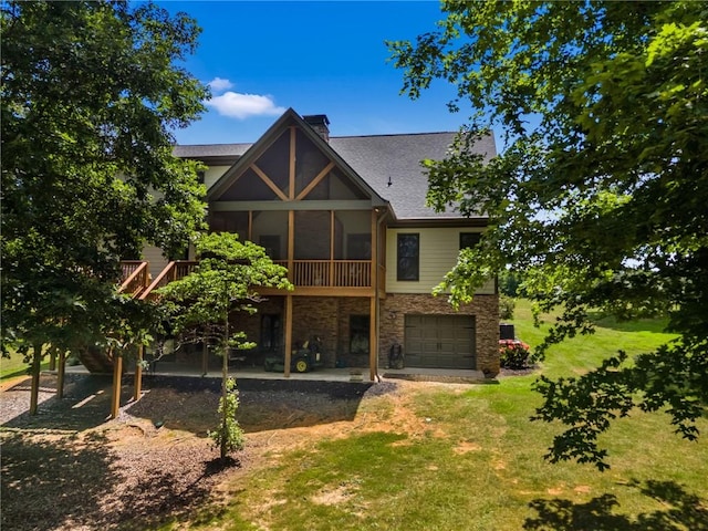 rear view of property with a sunroom, a deck, a garage, a patio, and a lawn