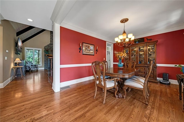 dining area featuring hardwood / wood-style floors, an inviting chandelier, and vaulted ceiling with beams