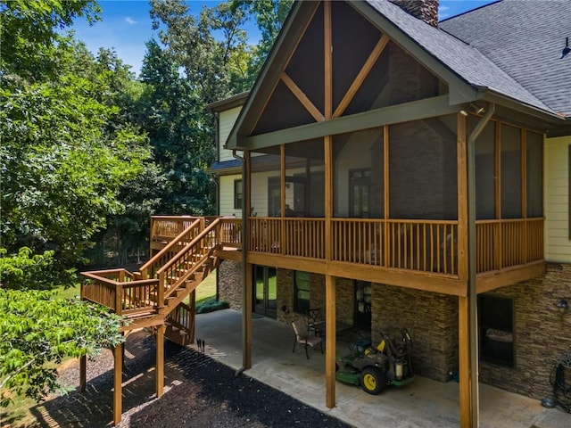 rear view of property with a wooden deck, a sunroom, and a patio