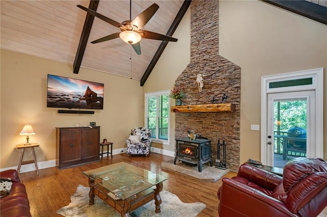 living room featuring wood-type flooring, beam ceiling, a wood stove, wood ceiling, and high vaulted ceiling