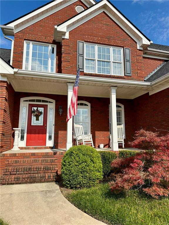 view of front of house featuring brick siding and a porch