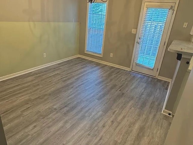 unfurnished dining area featuring plenty of natural light, dark wood-type flooring, and an inviting chandelier