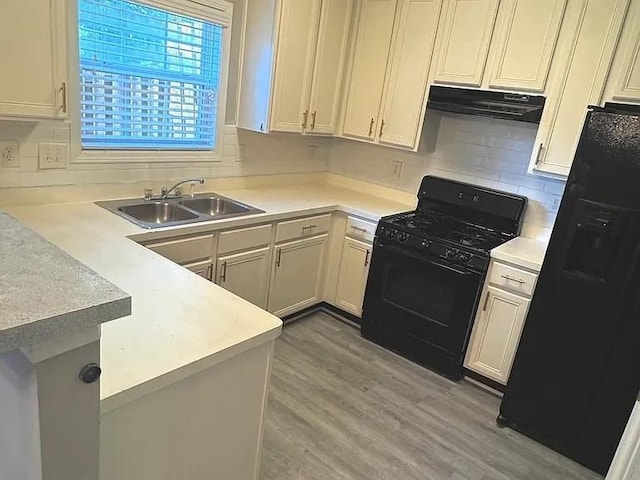 kitchen with hardwood / wood-style floors, black appliances, sink, range hood, and kitchen peninsula