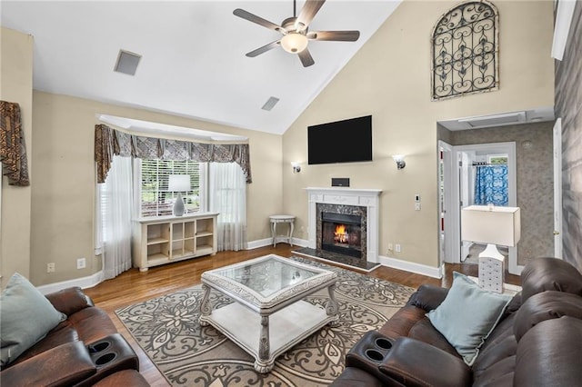 living area with ceiling fan, wood finished floors, a healthy amount of sunlight, and high vaulted ceiling
