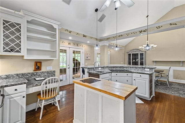kitchen featuring butcher block countertops, vaulted ceiling, an island with sink, and a sink
