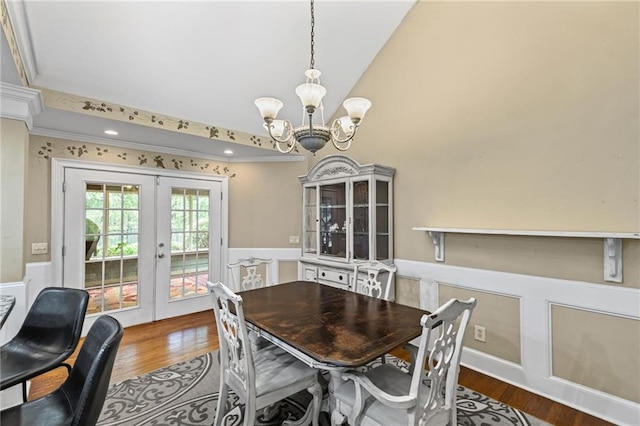 dining room featuring wood finished floors, a chandelier, french doors, and a wainscoted wall