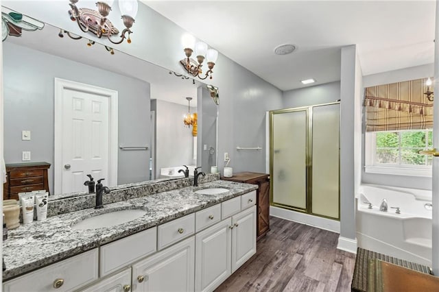 bathroom with an inviting chandelier, double vanity, a sink, and wood finished floors