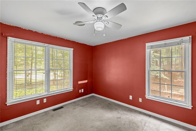carpeted spare room with baseboards, ceiling fan, and visible vents