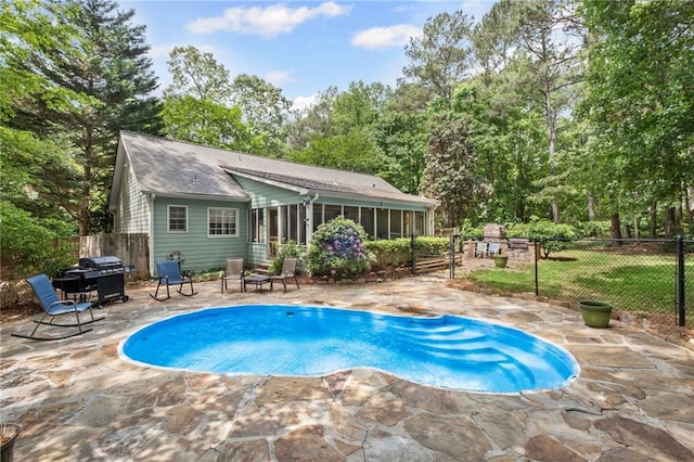 view of swimming pool with grilling area, a sunroom, fence, a fenced in pool, and a patio