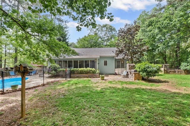 rear view of house with a storage shed, an outbuilding, a sunroom, a fenced backyard, and a yard