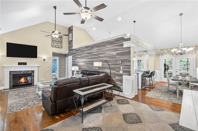 living room featuring wood finished floors, a fireplace, high vaulted ceiling, french doors, and ceiling fan with notable chandelier