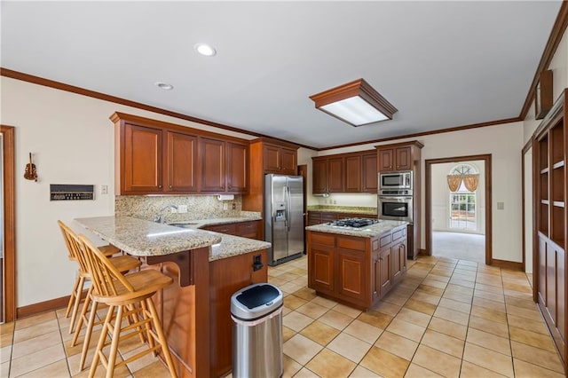 kitchen with decorative backsplash, a kitchen breakfast bar, appliances with stainless steel finishes, baseboards, and a peninsula