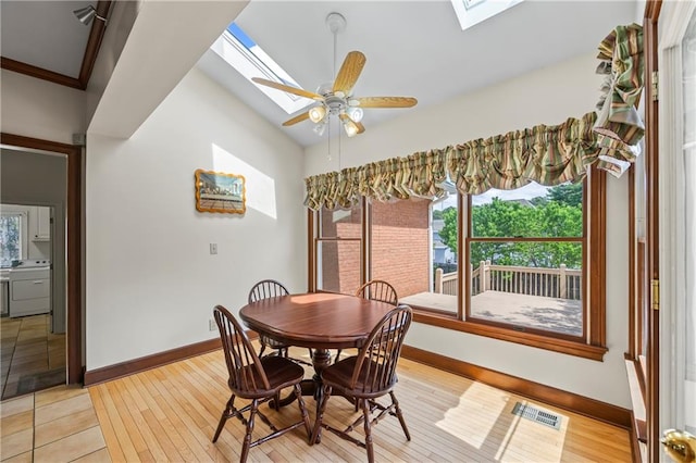 dining room with a skylight, baseboards, and light wood finished floors