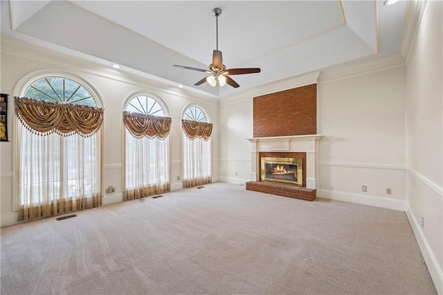 unfurnished living room featuring crown molding, a ceiling fan, a tray ceiling, and carpet floors