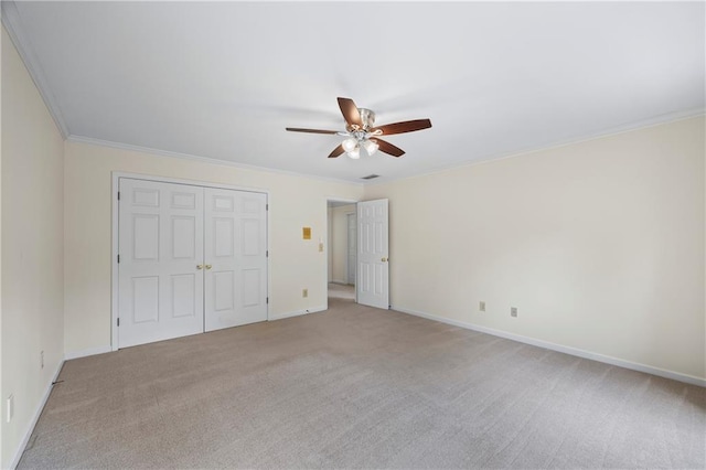 unfurnished bedroom featuring baseboards, light colored carpet, ornamental molding, and a closet