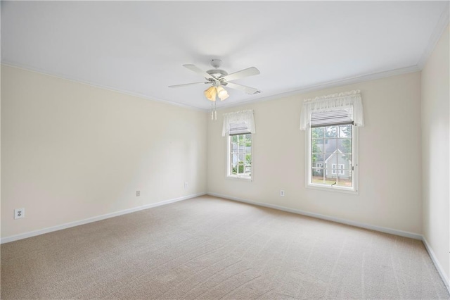 empty room with baseboards, crown molding, ceiling fan, and light colored carpet