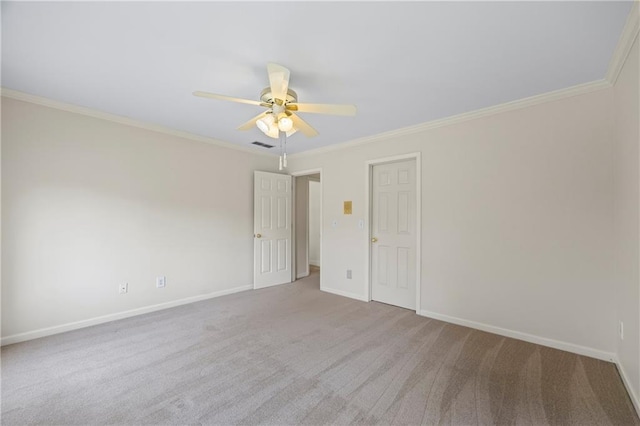 empty room featuring crown molding, carpet floors, a ceiling fan, baseboards, and visible vents